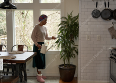 Black woman watering her plants at home